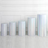 A row of five silver iridescent spandex cylinder stands displayed against a white wall.