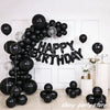 A large arrangement of black latex balloons spelling out HAPPY BIRTHDAY against a white wall.