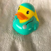 A bright yellow rubber duck bath toy with an orange beak and a silver spot resting on a light green background.