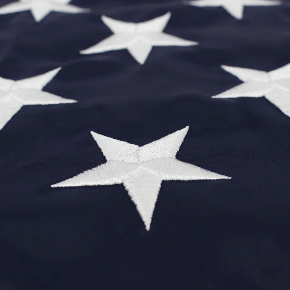 Close-up of a dark blue fabric featuring white embroidered stars in the pattern of an American flag.