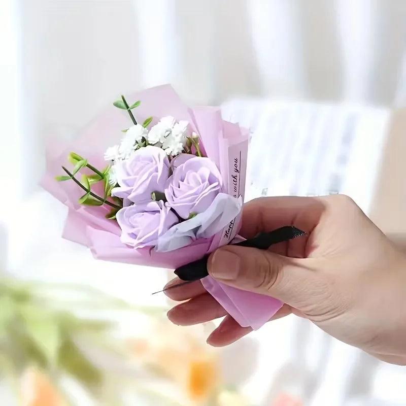 Une main tient un bouquet de roses artificielles violettes et de fleurs de remplissage blanches dans du papier rose.