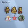 A set of enamel pins featuring religious iconography, including San Judas Tadeo and Jesus Christ.