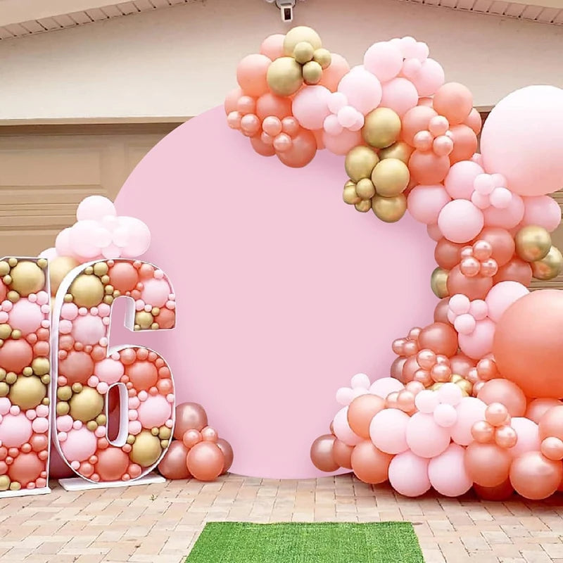 A pink balloon arch backdrop decorated with gold and peach balloons for an event