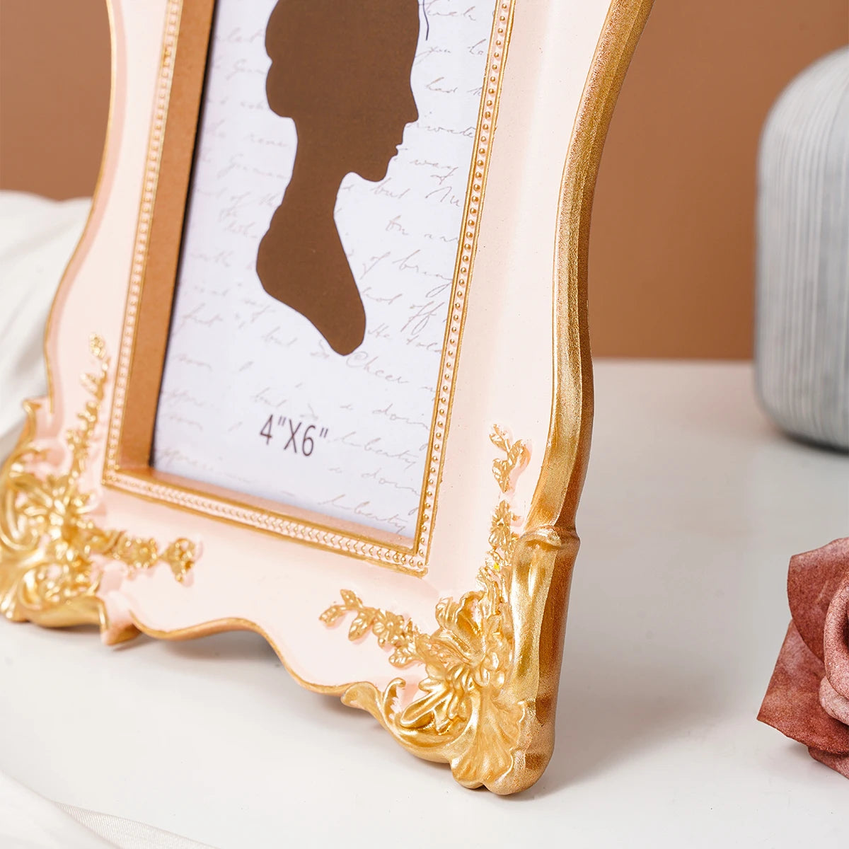 A light pink and gold decorative photo frame with a portrait silhouette displayed on a white surface.