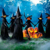 A group of witches in black robes with pointed hats and carved pumpkin faces standing in a misty green field.