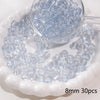 A clear glass dropper filled with small light blue spacer beads resting on a white dish.