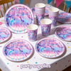 A table set featuring pink and purple plates and cups with K-Pop themed silhouettes for a birthday party.