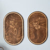 A pair of oval wooden wall decor pieces featuring delicate botanical line drawings on dark wood with natural edge finishing.