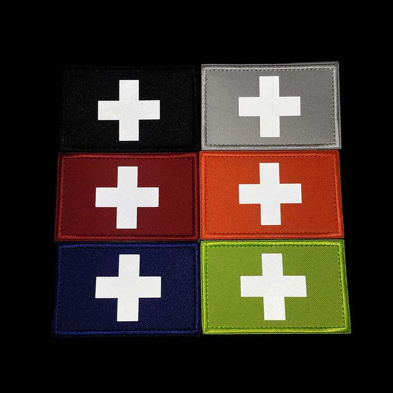 A set of four rectangular tactical morale patches featuring a white cross on black, gray, red, and green backgrounds.