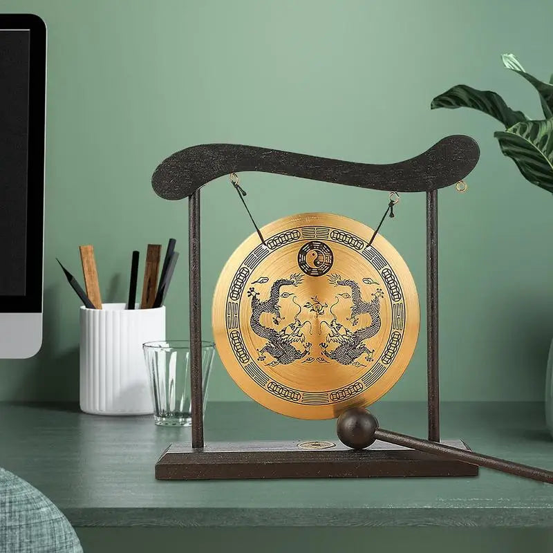 A bronze Feng Shui Zen table gong featuring dragon and Taiji symbols mounted on a dark wooden stand.
