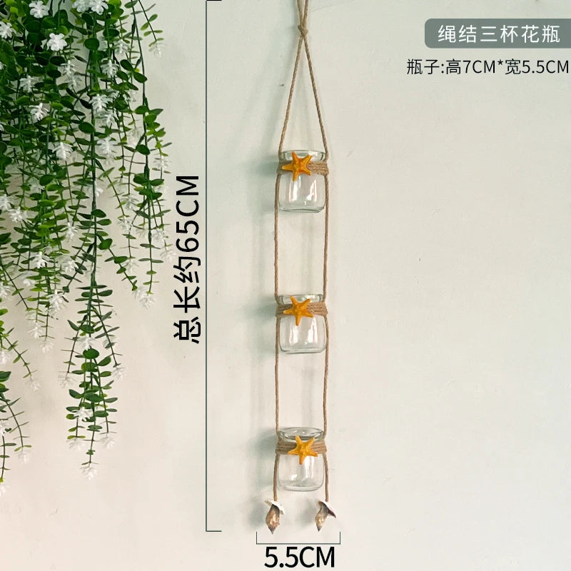 A hanging decorative glass terrarium with a string and an orange star charm, used for indoor plants.