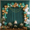 A floral and balloon decorated green backdrop for parties featuring gold and white balloons and greenery.
