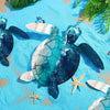 A blue and green turtle sculpture resting on a bright blue textured surface with green foliage in the background.
