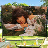 A woman with long brown hair wearing a white lace top is featured in an outdoor setting.