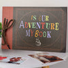 A handmade scrapbook album cover featuring the text Is Our Adventure My Book on a dark background with a textured border.
