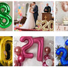 A collage of large foil number balloons in various colors and sizes, including 1, 8, 5, 20, 40, and 52, used for birthday and