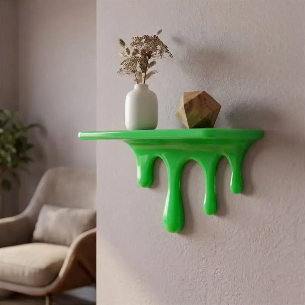A bright green drip floating shelf mounted on a white wall, displaying a small vase with dried flowers and a wooden geometric