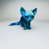 A blue articulated 3D printed figurine of a Siamese cat with large eyes and pointed ears.