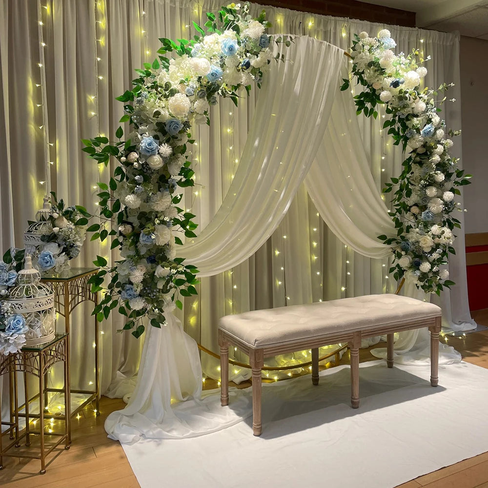 A floral archway decoration featuring white and blue roses and greenery for an event backdrop.