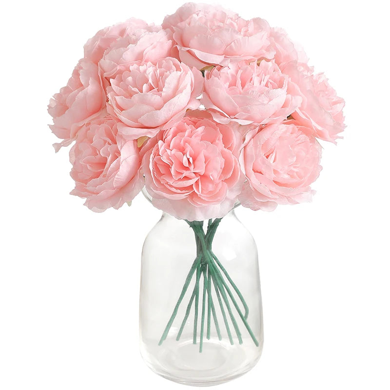 A bouquet of six pink artificial peony flowers arranged in a clear glass vase.