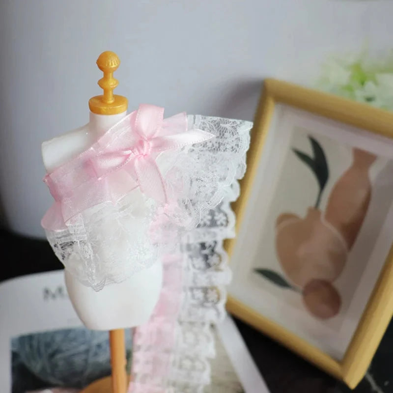 A white mannequin display featuring a delicate pink bow ruffle embroidery lace trim.