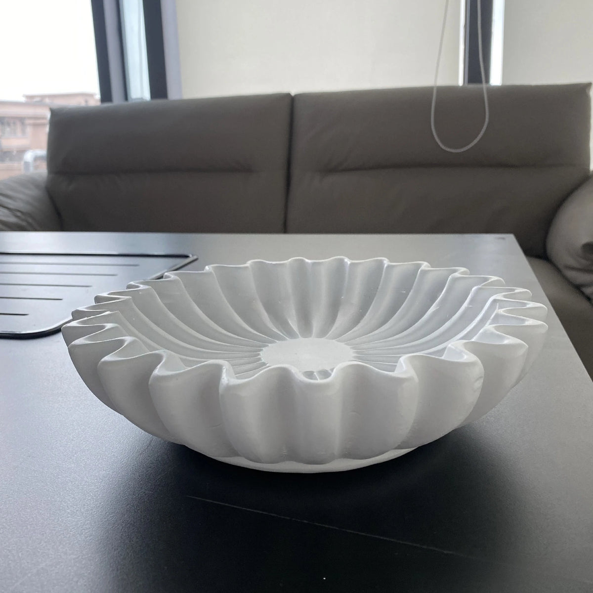 A white lotus leaf resin decorative bowl is displayed on a dark table.