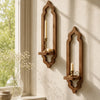 A rustic wooden wall shelf with an arched design holds a lit candle and a small bowl on a light-colored wall.