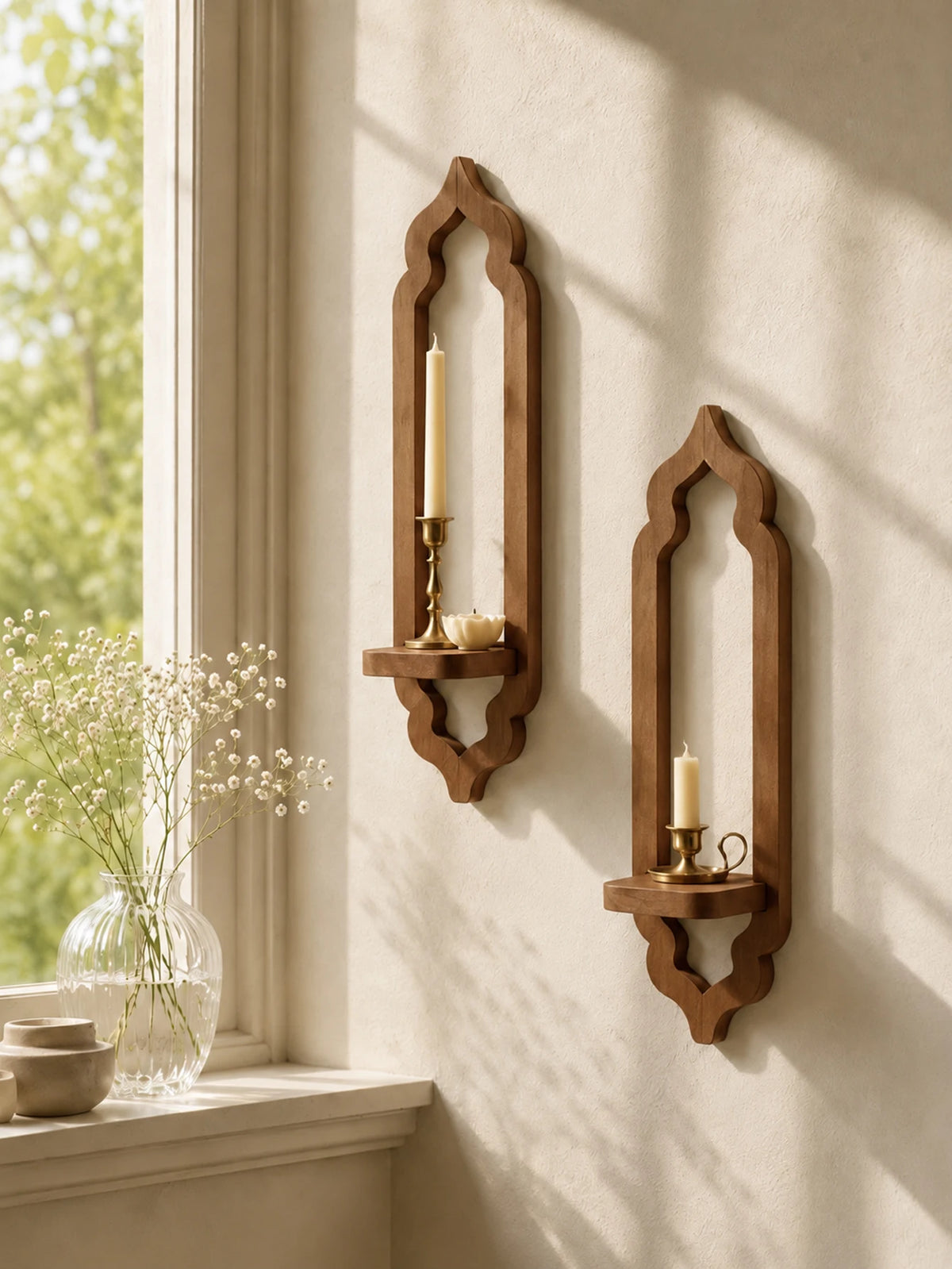 A rustic wooden wall shelf with an arched design holds a lit candle and a small bowl on a light-colored wall.