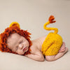 A newborn baby is sleeping wearing a handcrafted lion crochet outfit set with orange and yellow textures.