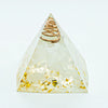 A clear quartz pyramid with a coiled gold wire inside, used for Reiki and meditation.