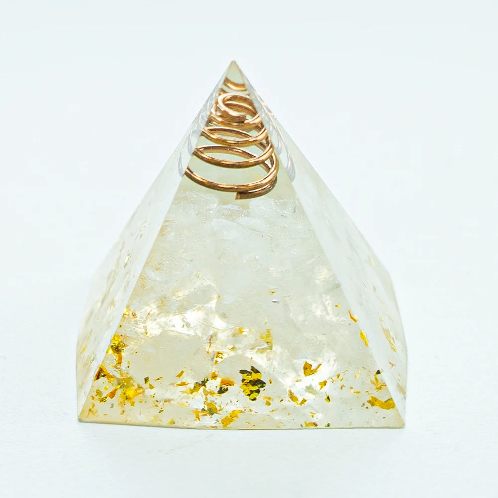 A clear quartz pyramid with a coiled gold wire inside, used for Reiki and meditation.