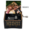 A wooden music box with a hand crank, featuring an illustration of a couple and gold leaf detailing.