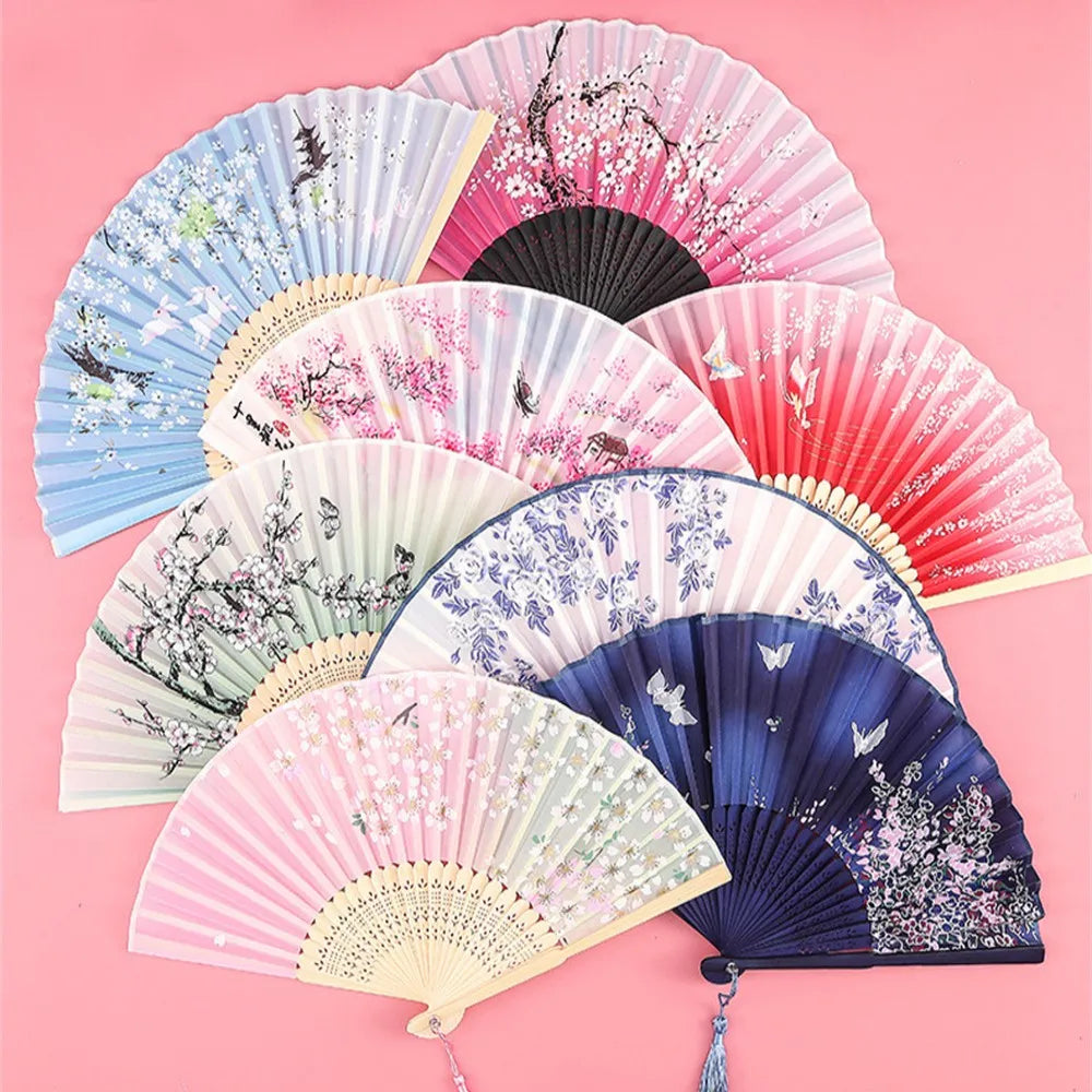A collection of vintage silk folding hand fans in various shades of pink, blue, and white with floral designs.
