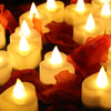 A close-up of glowing white heart-shaped tealight candles surrounded by red autumn leaves.
