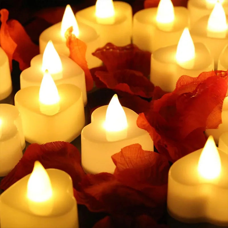 A close-up of glowing white heart-shaped tealight candles surrounded by red autumn leaves.