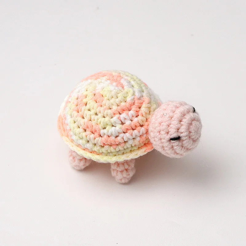 Handmade crocheted turtle plush with a mottled orange and white shell and pink body