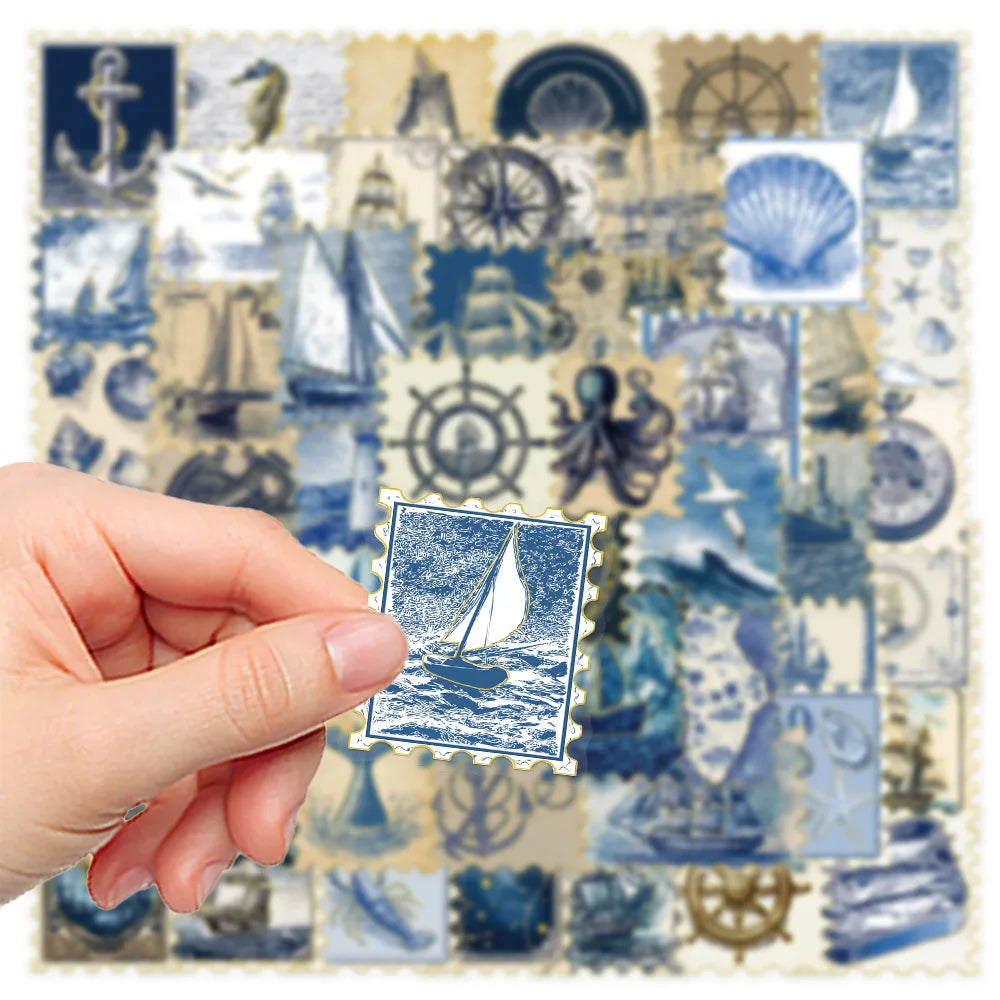 A hand holds a sheet of retro nautical foil stickers featuring ships, anchors, and lighthouses on a light background.