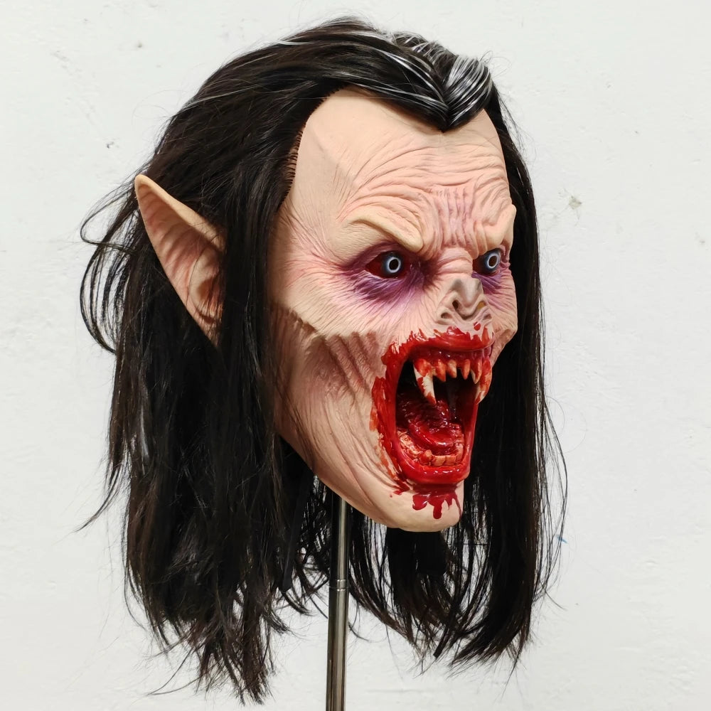 Lifelike vampire mask of a female creature with pale skin, long dark hair, and bloody fangs.