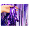 Une main tient des rideaux à franges arc-en-ciel violets et bleus.