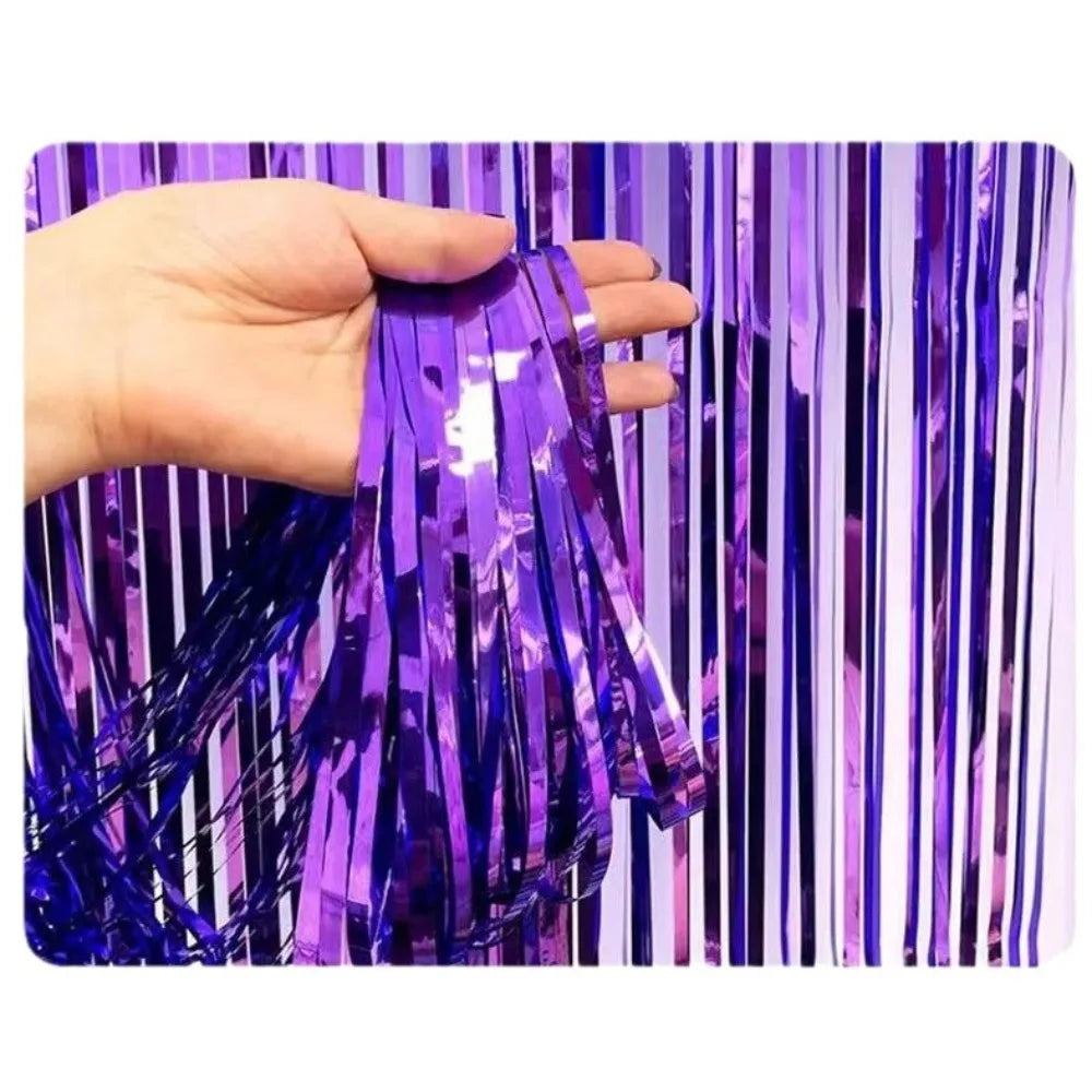 Une main tient des rideaux à franges arc-en-ciel violets et bleus.