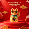 A yellow cat ornament with gold accents and a blue collar is displayed on a red circular base.