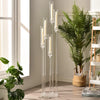 Tall 5-arm acrylic candelabra with white candles displayed next to a large green fern plant