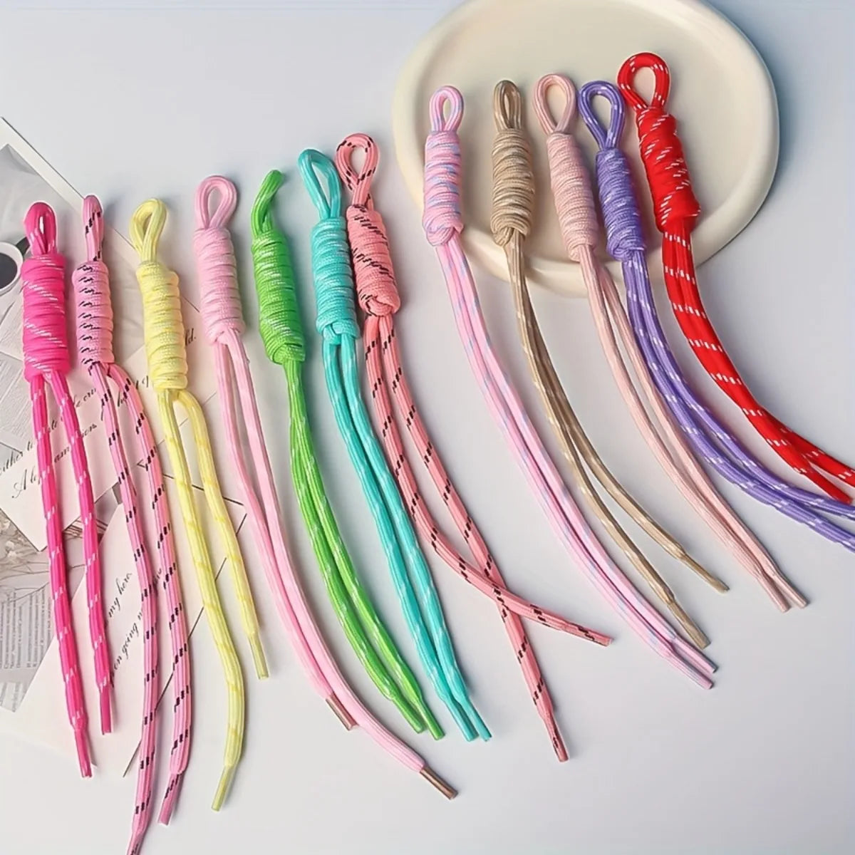 A collection of colorful nylon ropes in various shades including pink, yellow, green, and purple, laid out on a white plate.