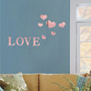 Pink heart wall stickers spelling LOVE on a blue wall next to a window