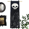 Tapis mural en macramé noir avec un crâne blanc et des franges longues