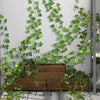 Artificial ivy vine garland cascading over a wooden planter against a gray wall.