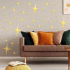 A living room wall decorated with gold star-shaped acrylic mirror stickers above a sofa.