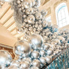 A dense archway made of metallic silver balloons and confetti accents inside a grand hall.