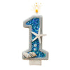 A birthday candle shaped like the number one decorated with blue glitter and seashells