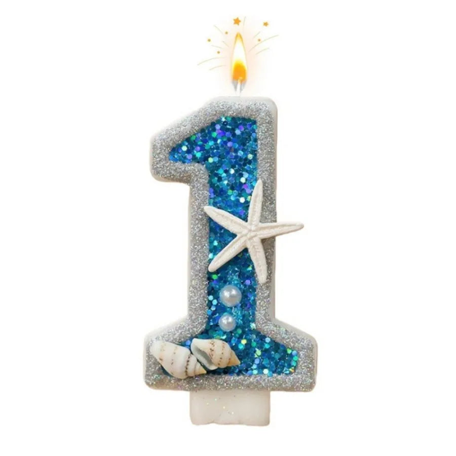 A birthday candle shaped like the number one decorated with blue glitter and seashells